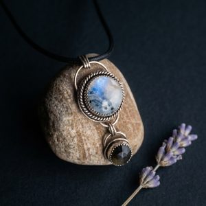 moonstone obsidian pendant propped on stone facing right handcrafted sterling silver jewelry