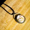 endritic Opal pendant displayed on a black cord necklace against a natural backdrop, emphasizing its fall-inspired design.