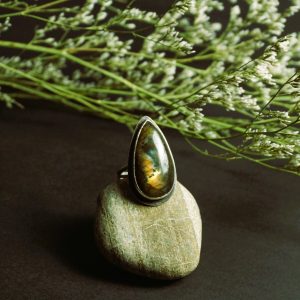 Bold spectrolite labradorite sterling silver ring on a natural stone in soft sunlight, showcasing aurora-like flashes