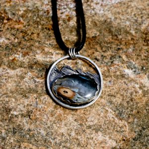Ocean jasper pendant on natural stone surface with mountain carving details.