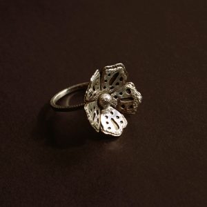 textured sterling silver flower ring facing right on dark background with hand-shaped petals and hammered band