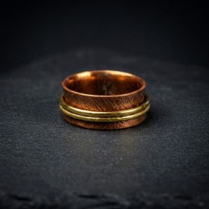 Handmade copper and brass spinner ring flat lay on dark background