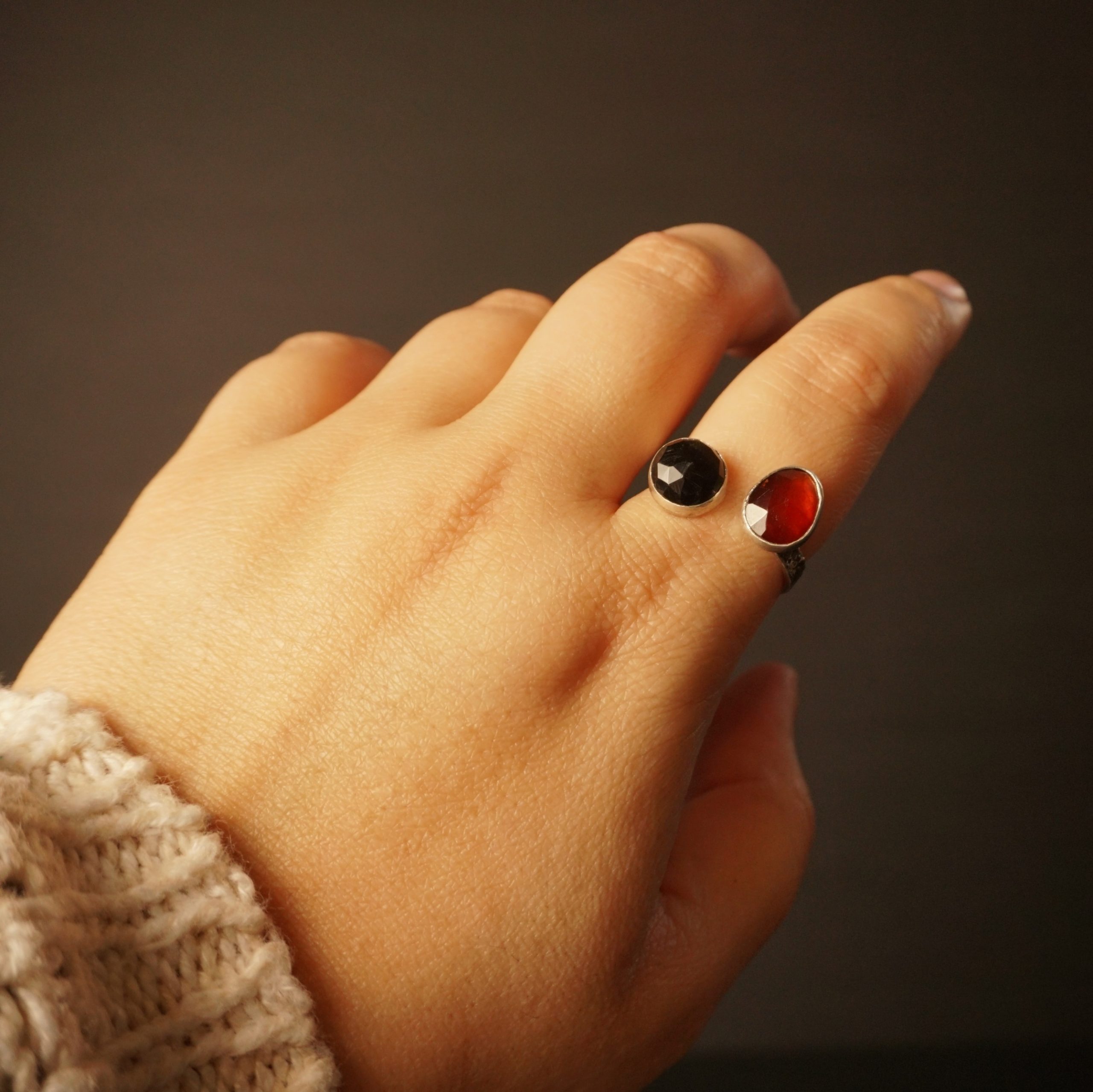 Solar Flare Ring – Garnet Obsidian Silver Ring on hand, bright light, showcasing bezel-set stones
